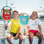 Novak 19 Racquet on a tennis ball bucket: "The Head Novak 19 Junior Tennis Racquet resting against a bucket of colourful mini-tennis balls."